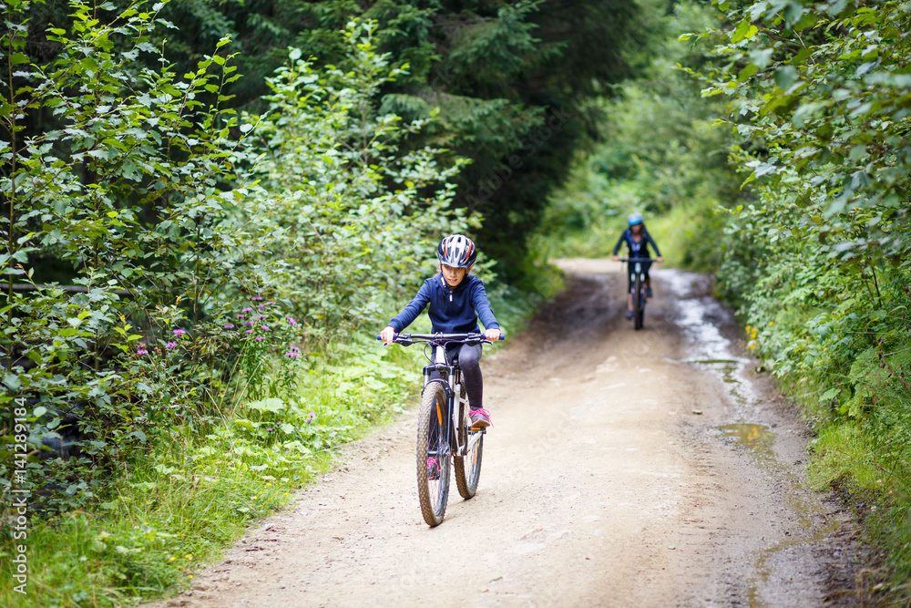 Naklejka premium Teenage girl in helmet riding the bicycle on mountain road
