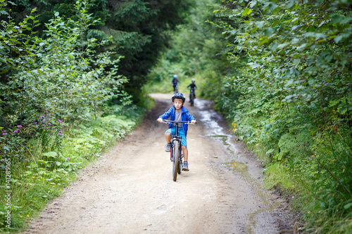 Small boy in helmet riding the bicycle on mountain road