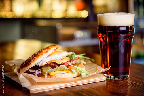 Hamburger and dark beer on a pub background.