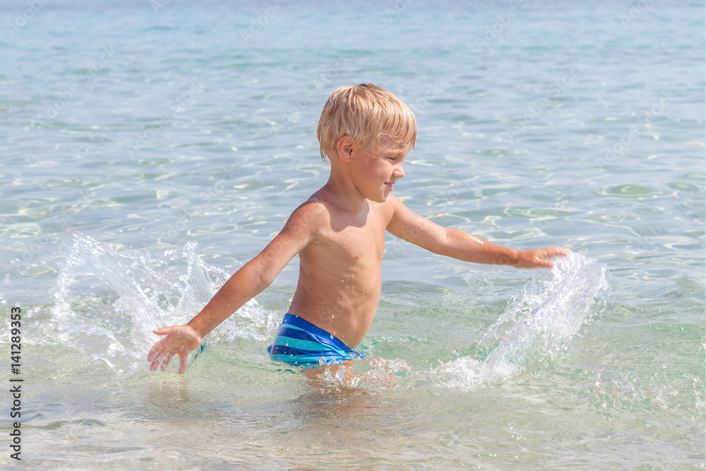 Little boy playing in the waves at sea on a sunny day Little boy playing in the waves at sea on a sunny day