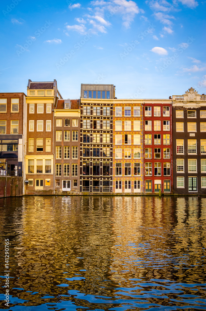 Traditional old buildings and boats at sunset in Amsterdam, Netherlands.