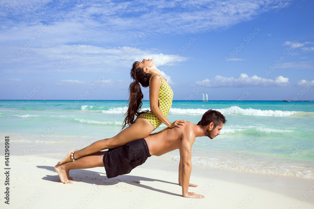 Couple practice yoga outdoors on the beach
