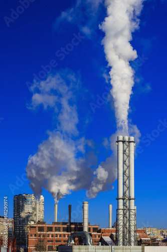 White smoke goes from a pipe on a background of blue cloudless sky