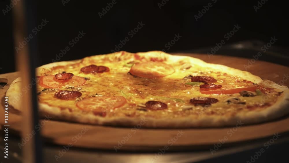 Baked homemade pizza placed on big wooden board with lifter in dark kitchen, beautiful warm light, close up Baked homemade pizza placed on big wooden board with lifter in dark kitchen, beautiful warm light, close up
