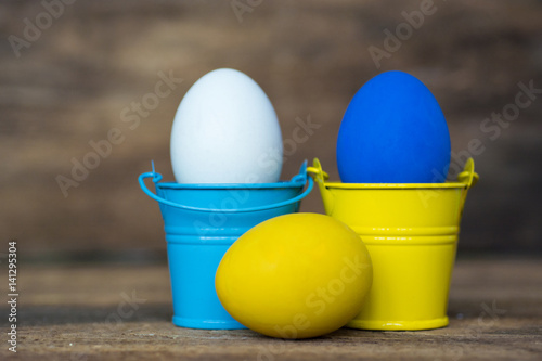 Blue and yellow Easter eggs in colored buckets, selective focus image, Card Happy Easter  