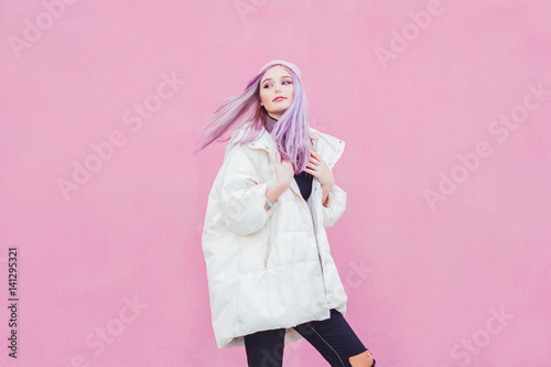 A beautiful girl with purple hair walks the streets of the city. Wearing a jacket, torn jeans and a hat.