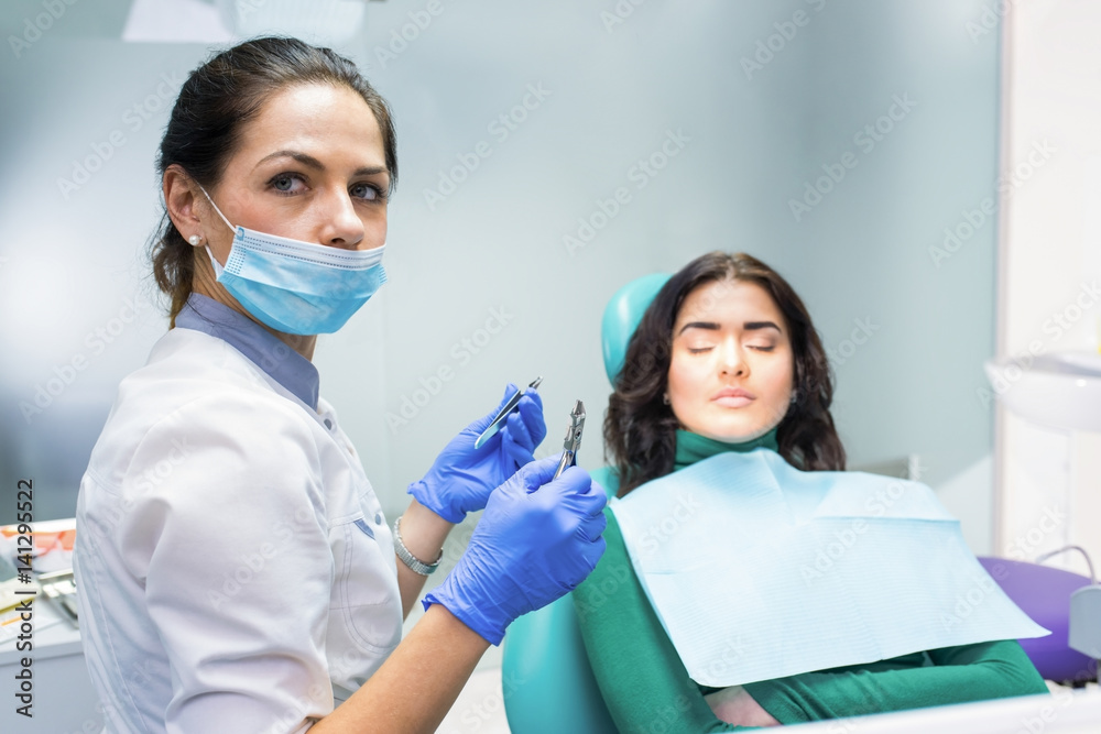 Female dentist holding pliers. Patient and doctor. Well-paid job in healthcare.