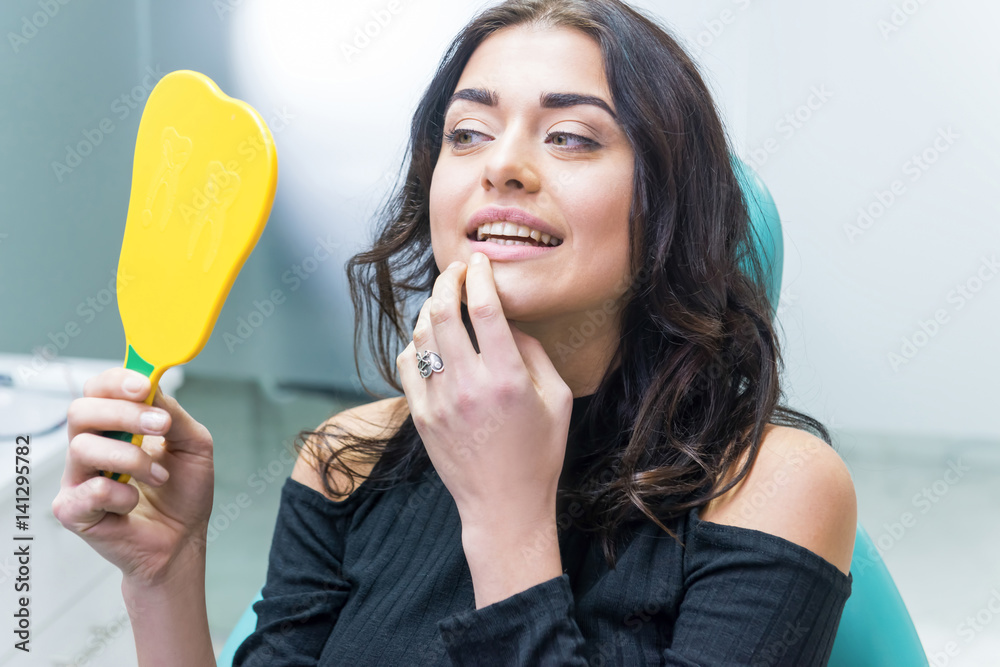 Woman checking teeth in mirror. Female at the dentist office. Woman checking teeth in mirror. Female at the dentist office.