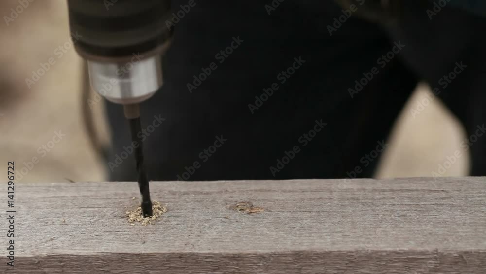 Drill an electric drill hole in a wooden bar