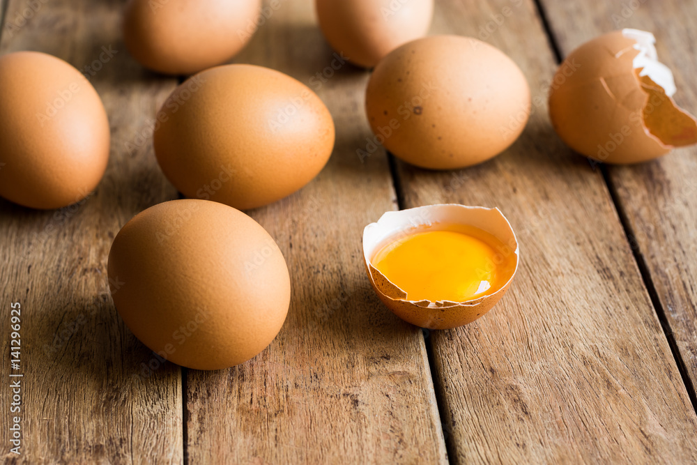 Fresh organic eggs scattered on wood kitchen table, cracked shell with open yolk, soft daylight, baking, Easter concept Fresh organic eggs scattered on wood kitchen table, cracked shell with open yolk, soft daylight, baking, Easter concept