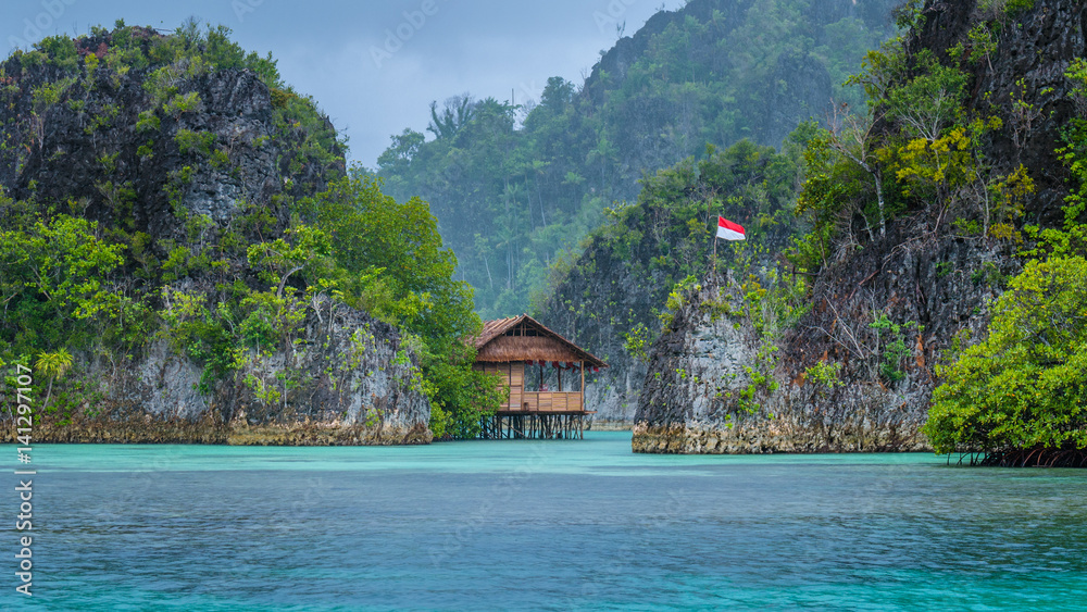 Bamboo Hut between some Rocks under Rain in Bay, Painemo Islands, Raja Ampat, West Papua, Indonesia Bamboo Hut between some Rocks under Rain in Bay, Painemo Islands, Raja Ampat, West Papua, Indonesia