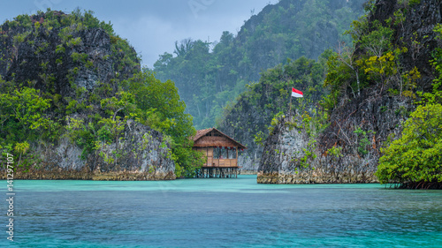 Bamboo Hut between some Rocks under Rain in Bay, Painemo Islands, Raja Ampat, West Papua, Indonesia