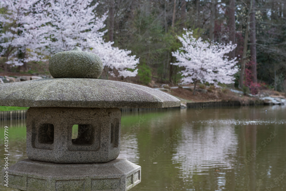 Japanese garden scene with cherry blossoms and sculpture.