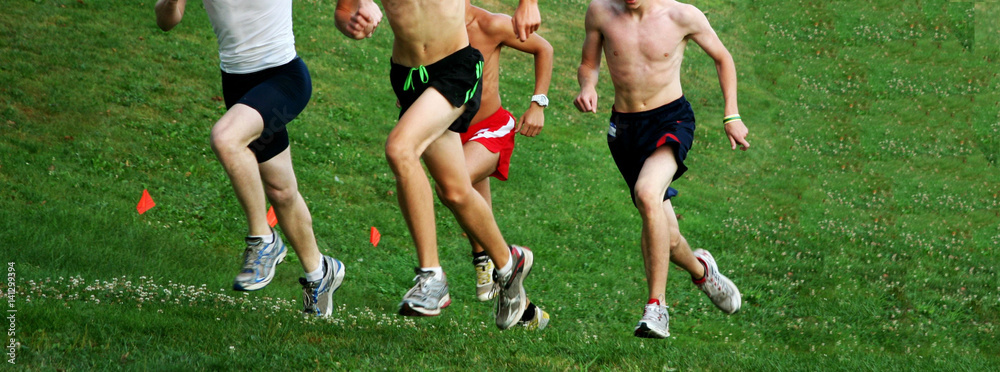 Four boys racing uphill during a cross country race Four boys racing uphill during a cross country race
