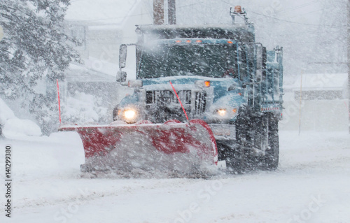 Snow plow with a red plow working in a blizzard photo