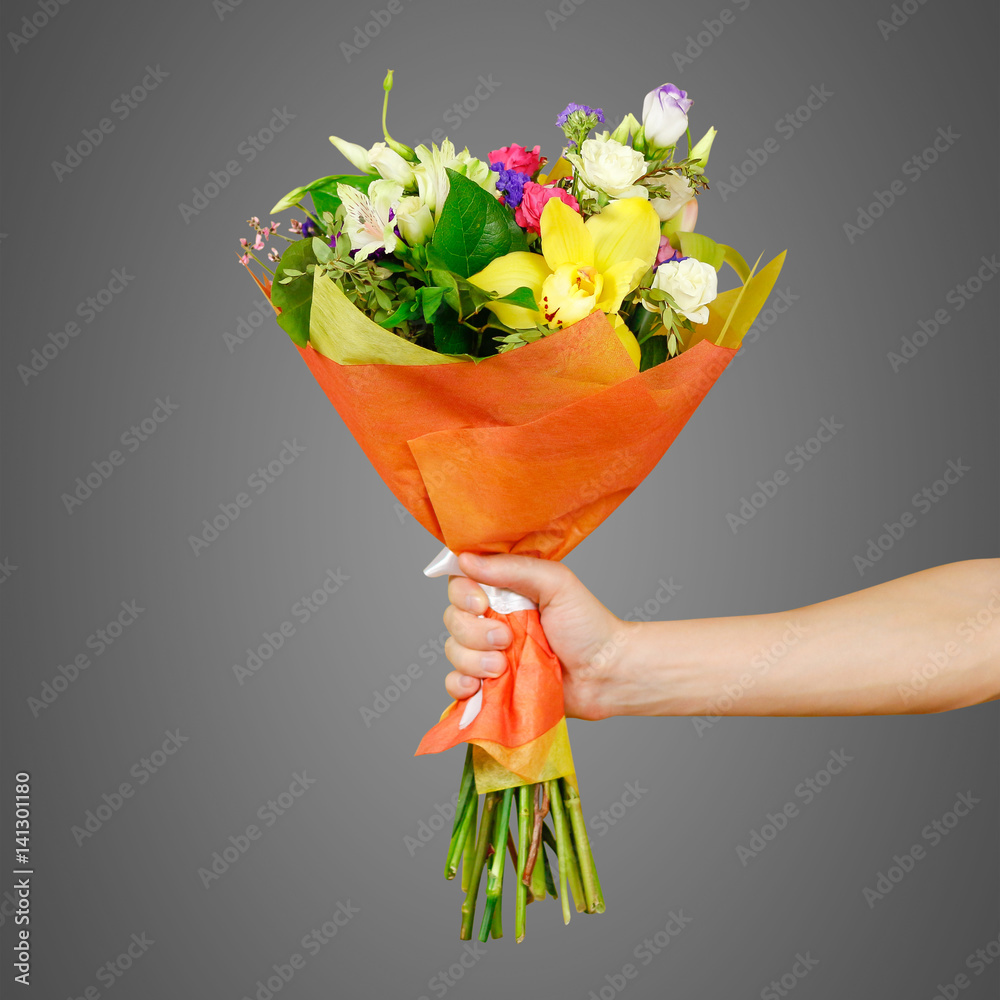 Hand holding a beautiful bouquet of different flowers. Isolated on a