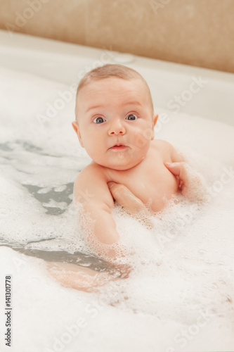 Portrait of white Caucasian middle age father taking bath together with small newborn baby, happy lifestyle candid, daily routine