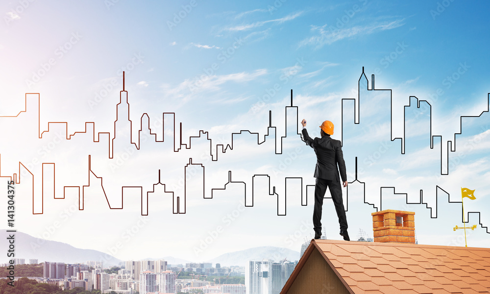 Man architect draw silhouette of modern city on blue sky. Mixed media