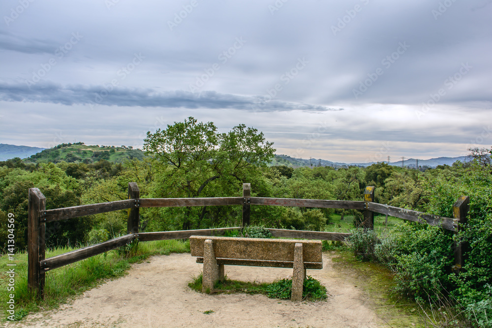 viewing platform with wood fence, mountains under cloudy sky