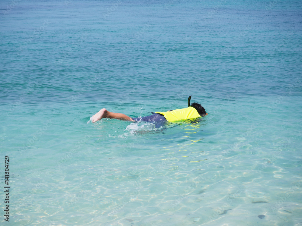 Asian man diving underwater on summer beach.