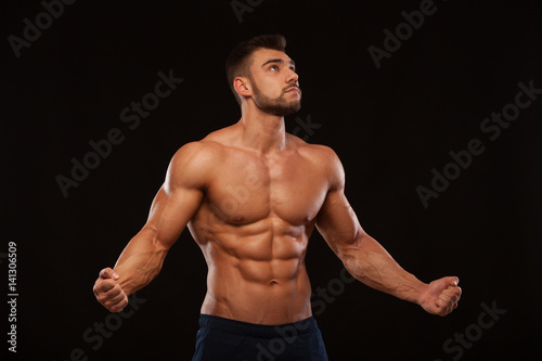Strong Athletic Man Fitness Model Torso showing six pack abs. isolated on black background with copyspace