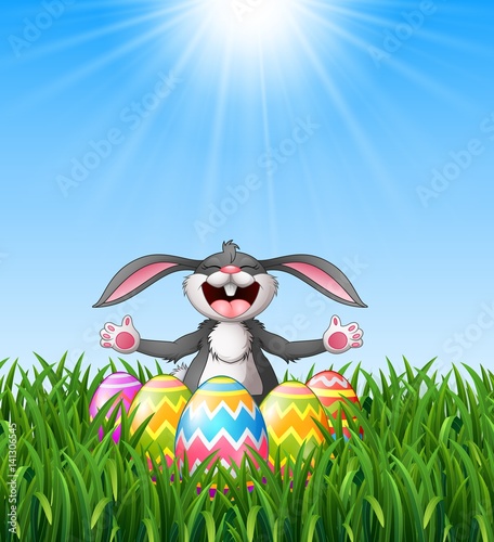 Cartoon rabbit laughing with easter eggs in the grass