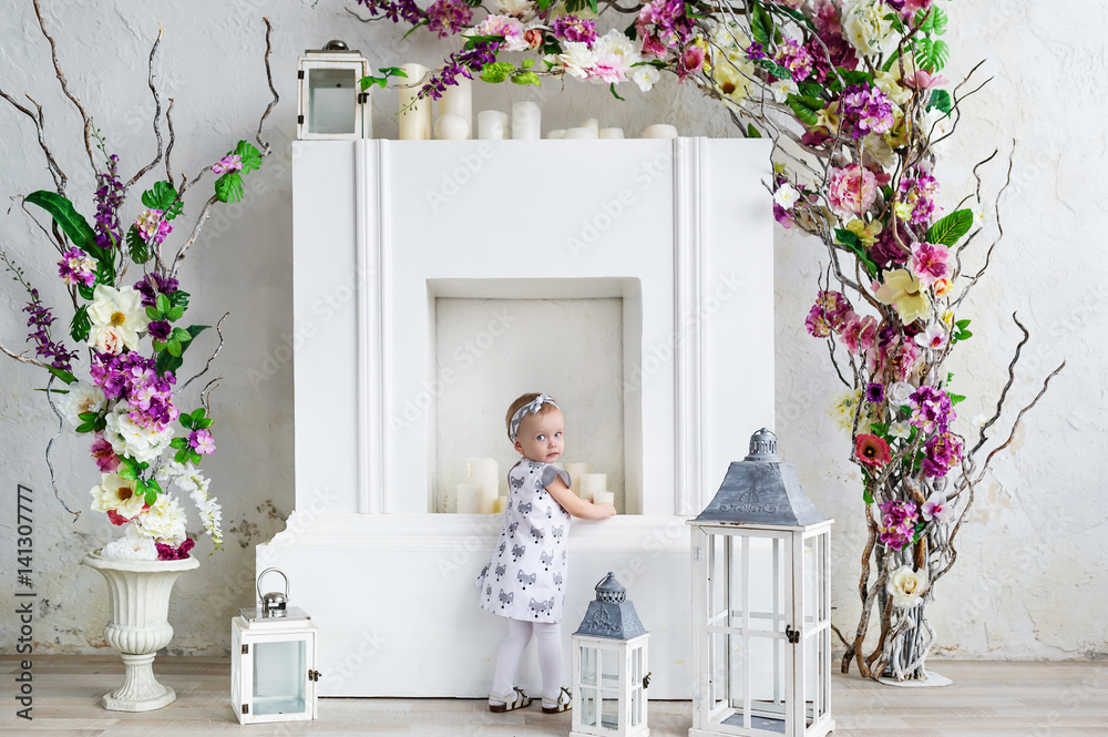 Beautiful baby girl in an elegant dress with flowers studio