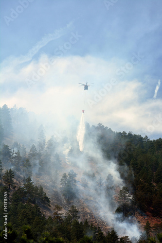 Chinook Firefighting Helicopter Drops Water on a Forest Fire in the Mountains