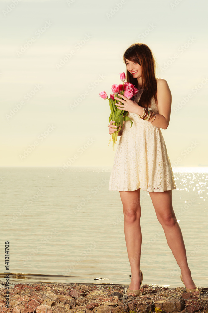 Beautiful woman holding bouquet of flowers on beach Stock Photo | Adobe ...