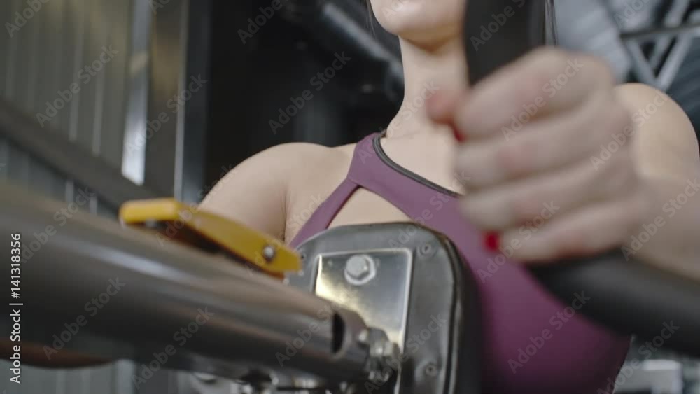 Tilt down of fit beautiful sportswoman working out on chest press machine in gym Tilt down of fit beautiful sportswoman working out on chest press machine in gym