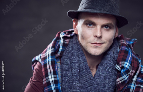 Portrait of stylish positive male dressed in a hat and a scarf.