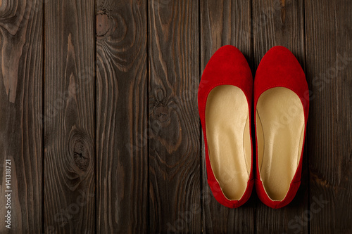 Red women's shoes (ballerinas) on wooden background.