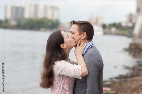 The girl kisses her boyfriend. He looks sadly aside