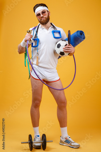 Happy satisfied man champion holding golden cup and sports equipment photo