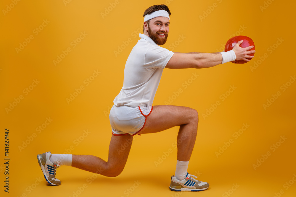 Cheerful young sportsman make sport exercises holding ball.