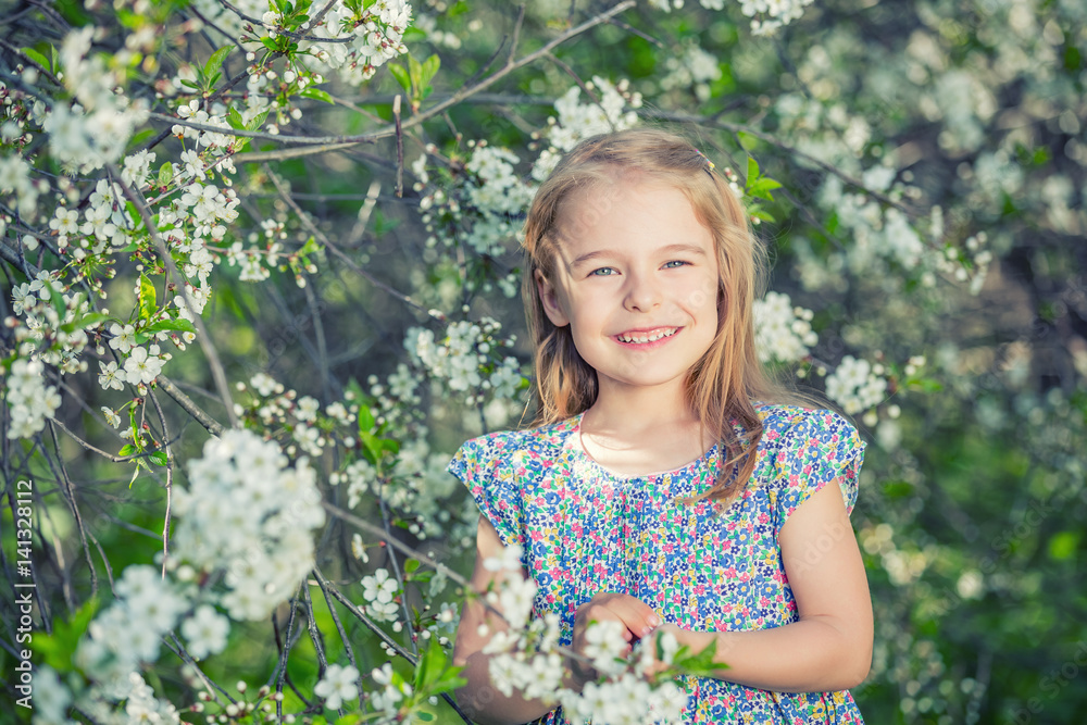 Happy little girl playing in spring cherry garden Happy little girl playing in spring cherry garden