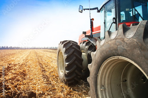 Fototapeta Nowoczesny czerwony traktor w polu z bliska.