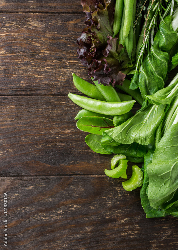 Background with assorted green vegetables on wooden table top. Healthy food concept with copy space. Background with assorted green vegetables on wooden table top. Healthy food concept with copy space.