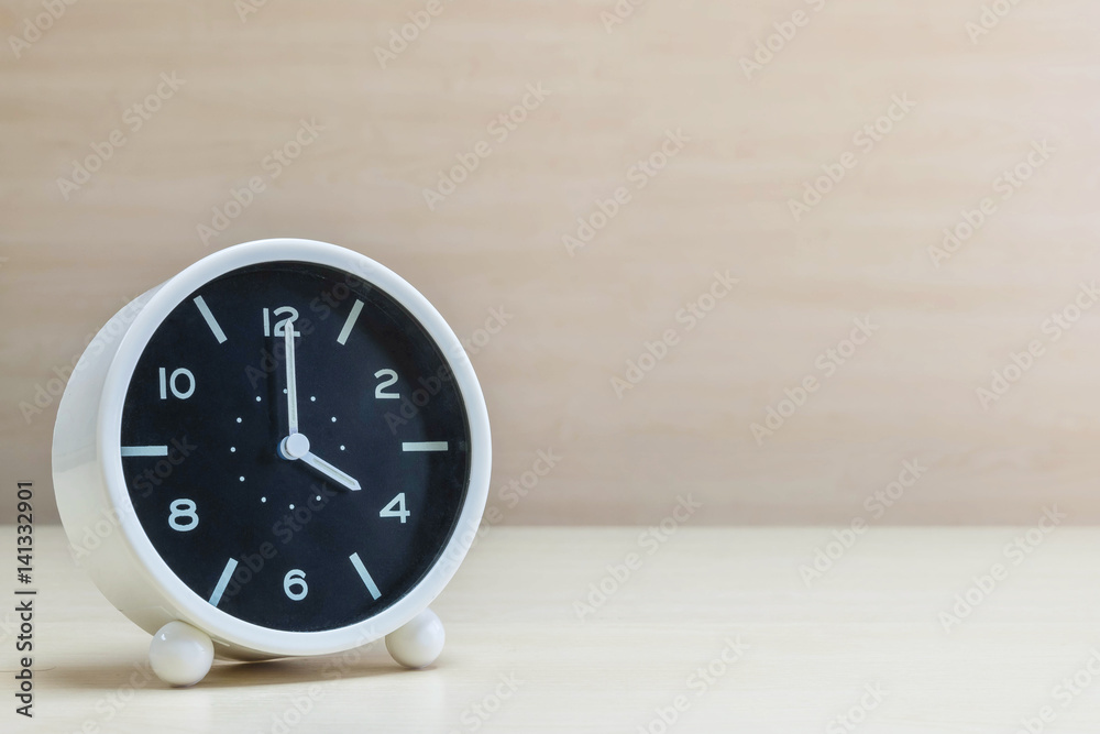 Closeup alarm clock for decorate in 4 o'clock on brown wood desk and wall textured background with copy space Closeup alarm clock for decorate in 4 o'clock on brown wood desk and wall textured background with copy space