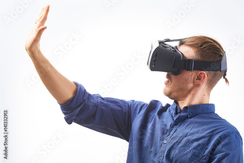 Young man Using VIrtual Reality Glasses for first time looking on his hand thru VR Glasses studio shot on white background