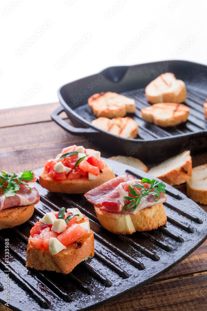 Set of bruschetta on black grill pan on wooden background. Tasty antipasto. Set of bruschetta on black grill pan on wooden background. Tasty antipasto.