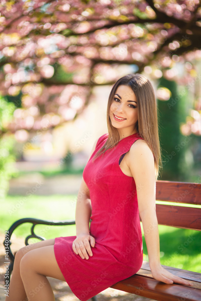 Beautiful girl posing to the photographer against the background of blooming pink trees. Spring. Sakura. Beautiful girl posing to the photographer against the background of blooming pink trees. Spring. Sakura.