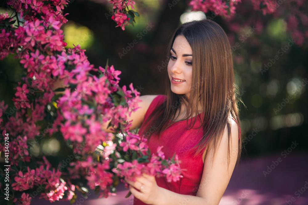 Beautiful girl posing to the photographer against the background of blooming pink trees. Spring. Sakura. Beautiful girl posing to the photographer against the background of blooming pink trees. Spring. Sakura.