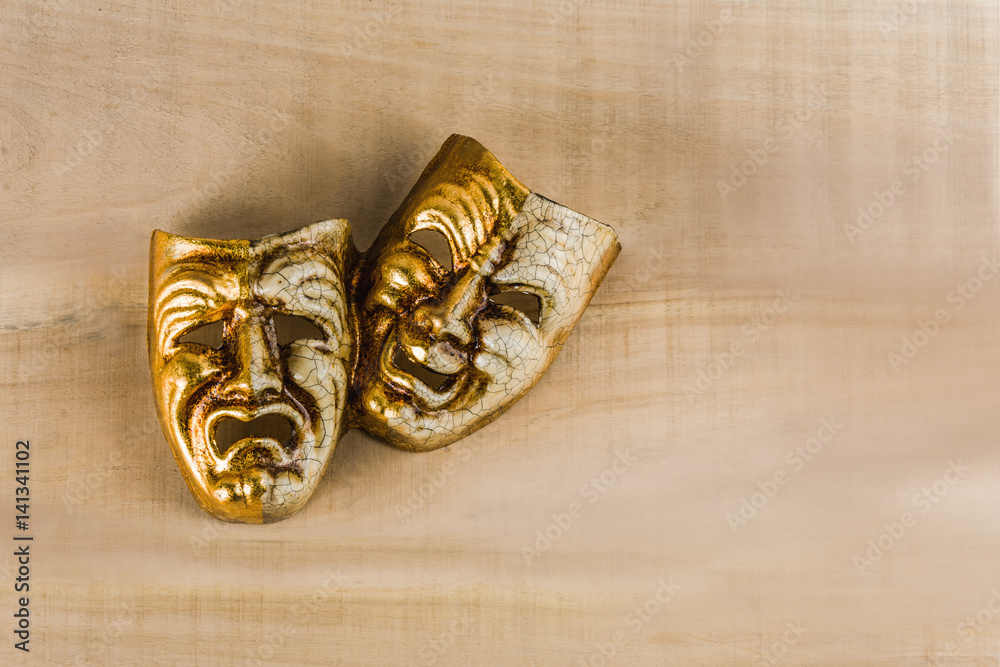 Fototapeta premium Two theatrical masks of joy and sadness lie on a wooden table