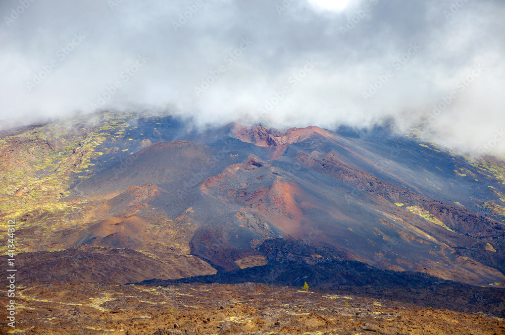 view of lifeless slopes of the sleeping volcano, top it is closed by smoke and clouds