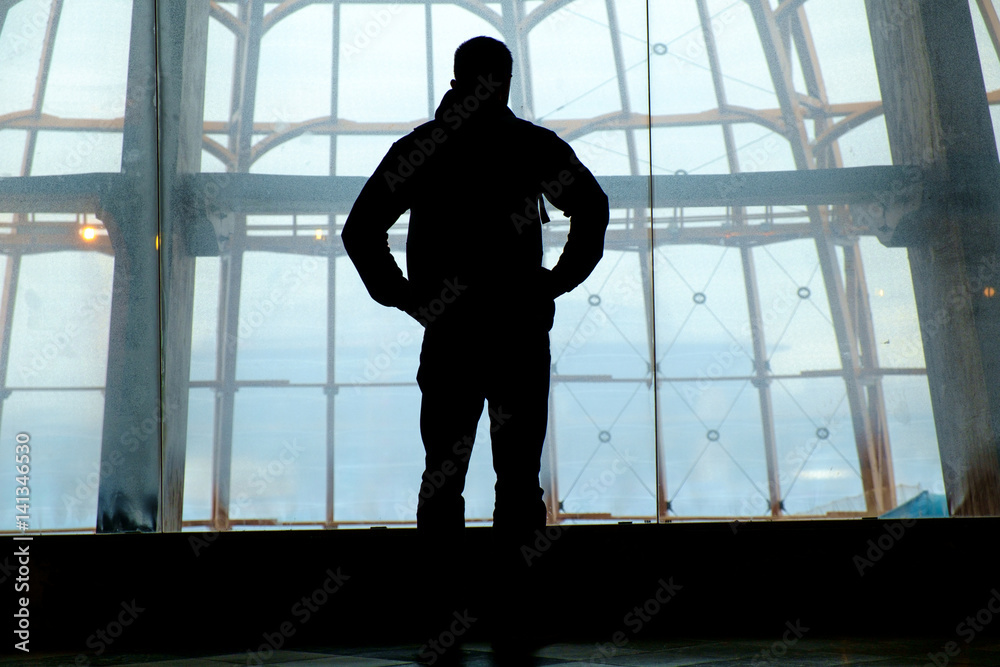 Fototapeta premium Silhouette of man standing over window