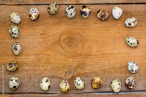 frame made of quail eggs on old brown wooden background.