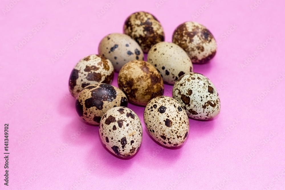 a lot of quail eggs on a pink background.