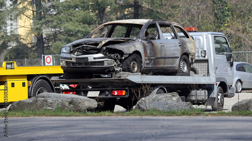 Fire damage on wrecked car loaded on a flatbed tow truck at the scene