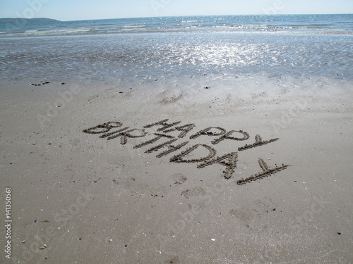 Happy birthday scripted in coast sand